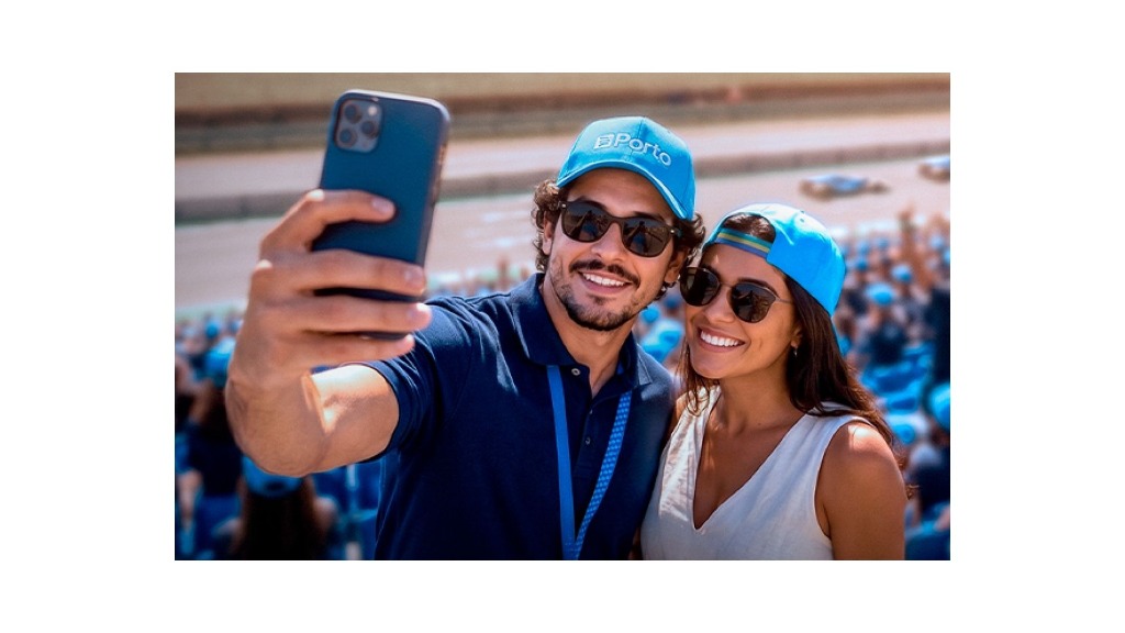 Casal tirando selfie sorrindo com boné da Porto Seguro